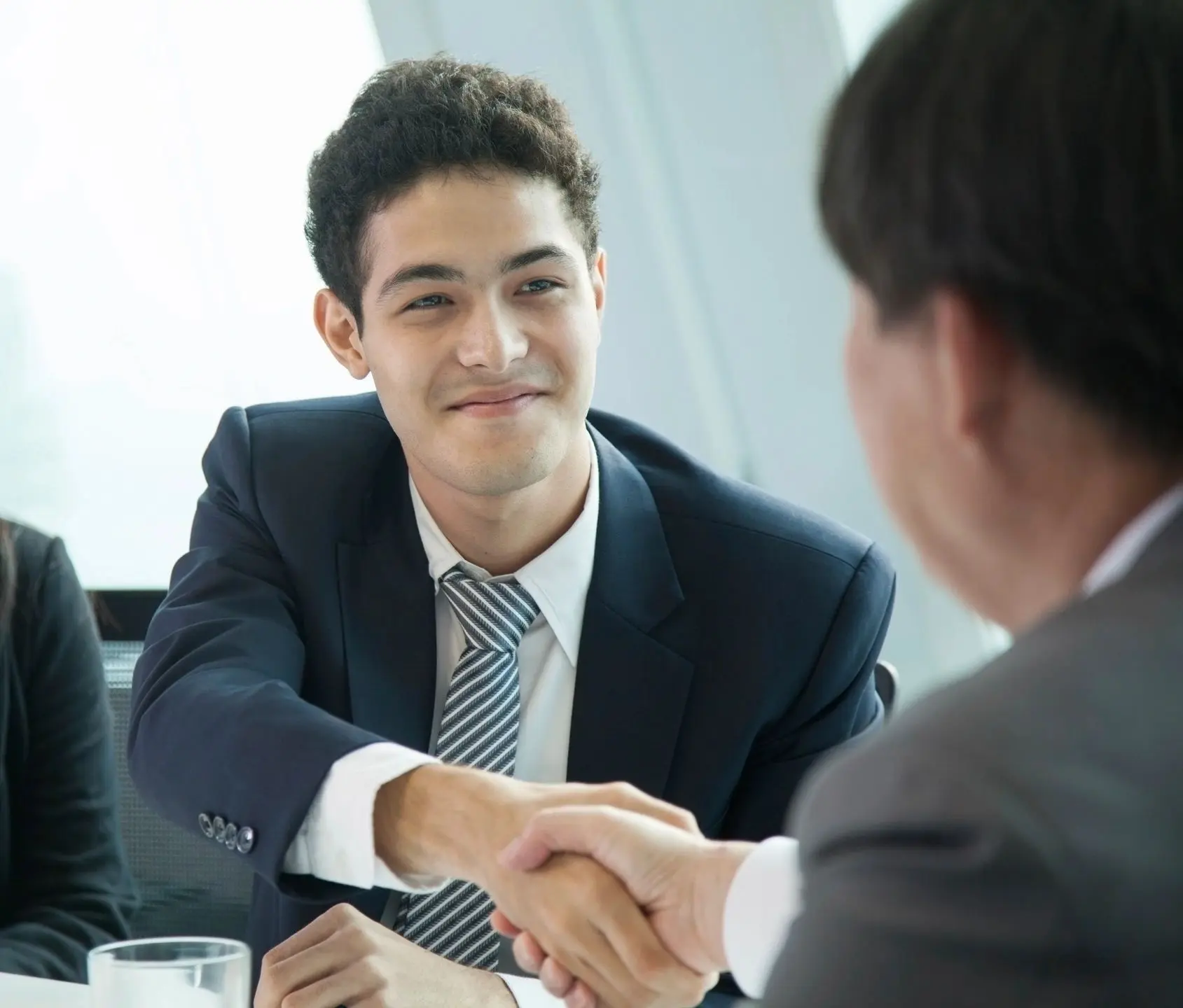 fm=f_856 A man in suit shaking hands with another person.