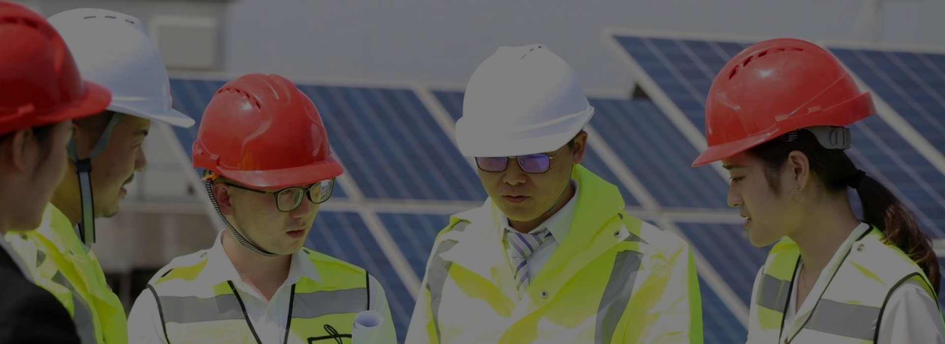 img2 Two men in hard hats and reflective jackets standing next to a solar panel.